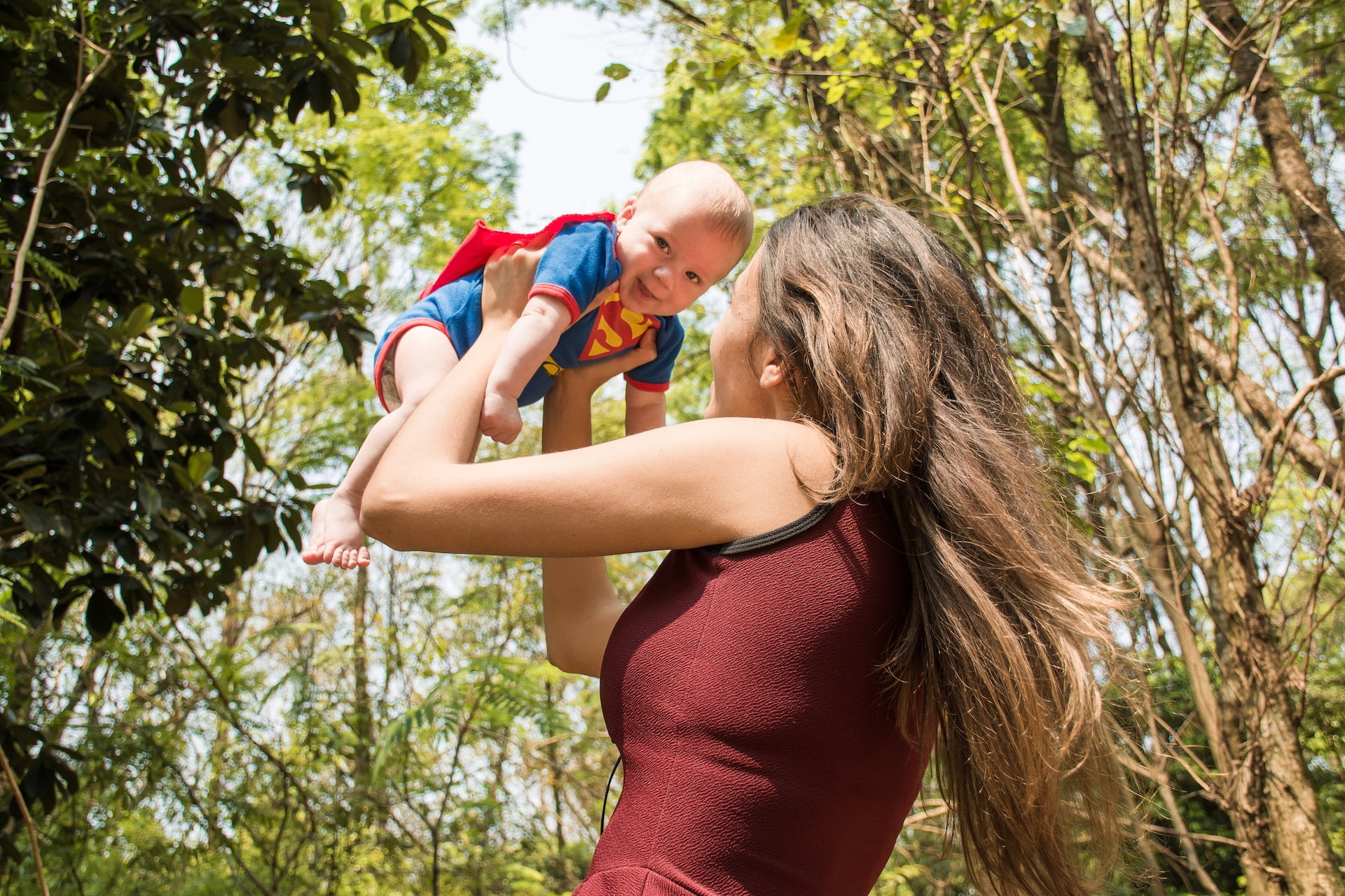 happy, sunny, play, lifting child over head, mother, green trees